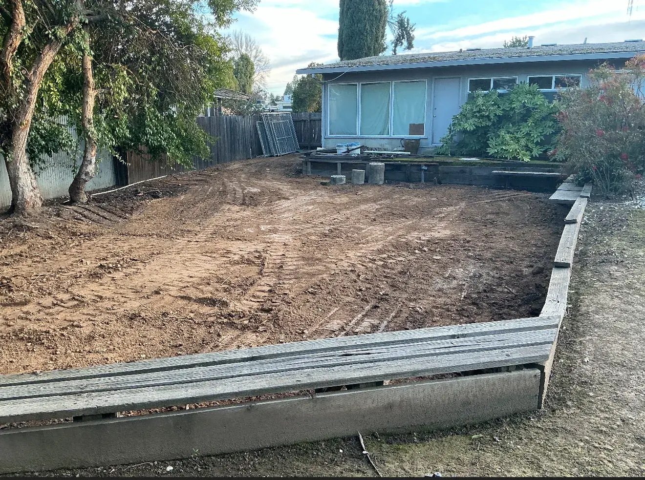 Cleared and graded backyard pad where Sacramento pool once was, ready for new use