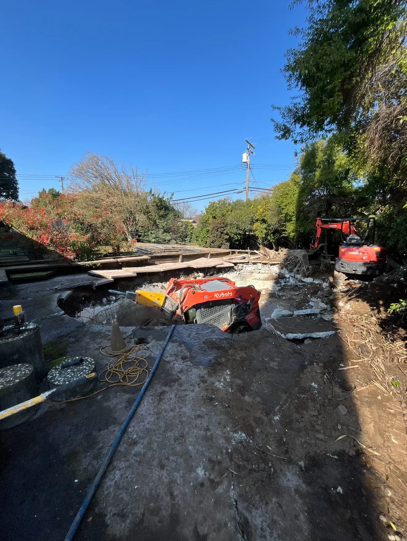 Kubota skid steer with hydraulic breaker demolishing concrete pool shell in Sacramento